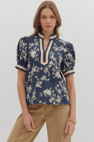 Woman wearing a blue floral blouse with beige accents on a white background
