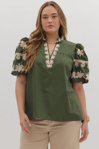 Woman wearing a green blouse with floral embroidery on a white background