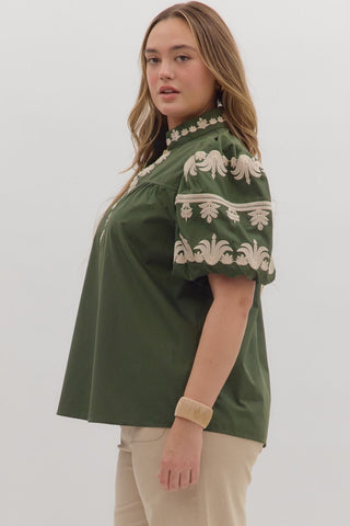 Woman wearing a green embroidered blouse against a white background
