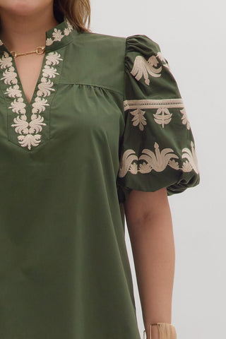 Green dress with white embroidery on a plain background