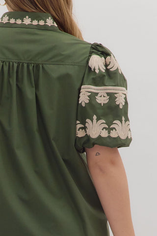 Green shirt with white floral embroidery on a plain background