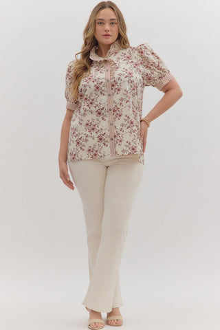 Woman wearing a floral blouse and beige pants on a white background