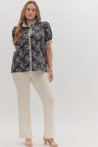 Woman wearing a floral blouse and beige pants on a white background