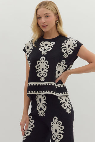 Woman wearing a black outfit with white pattern on a plain background