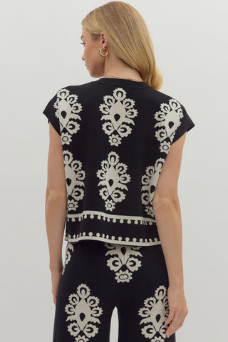 Person wearing a black top and pants with white pattern on a plain background