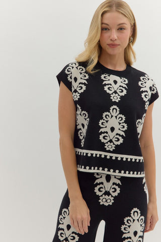 Woman wearing a black dress with white pattern against a white background