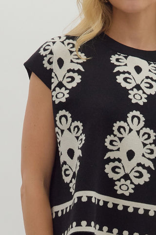 Black dress with white floral patterns on a plain background