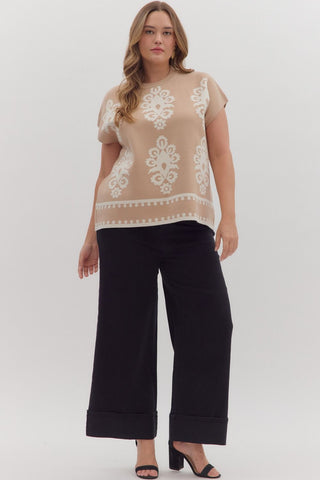 Woman wearing a beige top with white lace details and black pants on a white background