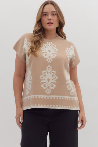 Woman wearing a beige top with white lace pattern on a plain background
