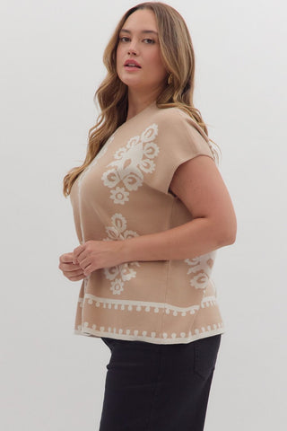 Woman wearing a beige top with white lace details on a plain background