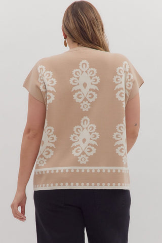 Woman wearing a beige top with white lace patterns on a plain background