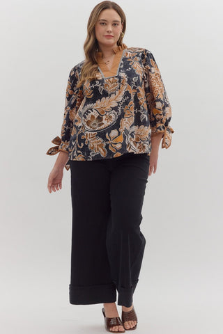 Woman wearing a patterned blouse and black pants on a white background