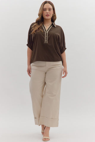 Woman wearing a brown top and beige pants on a white background