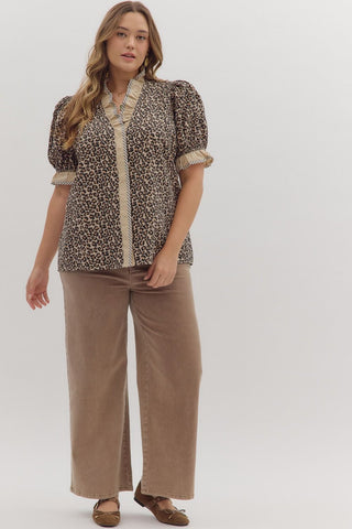 Woman wearing a leopard print blouse and beige pants on a white background