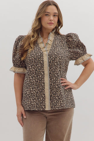 Woman wearing a leopard print blouse with ruffled details on a plain background