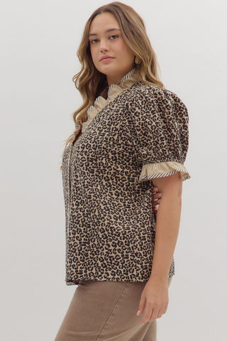 Woman wearing a leopard print blouse with ruffled sleeves on a plain background