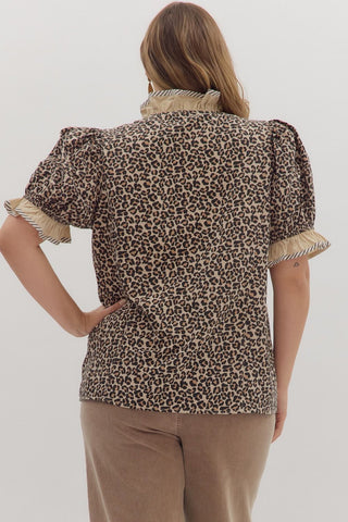 Person wearing a leopard print blouse with ruffled sleeves on a white background