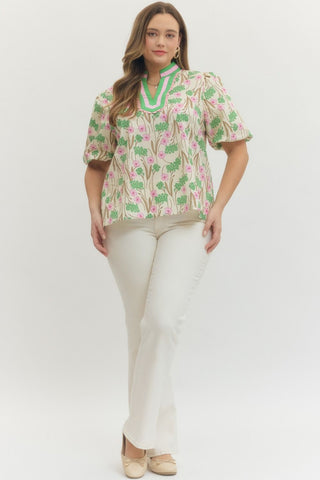 Woman wearing a floral blouse and white pants on a white background