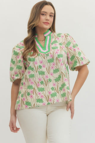 Woman wearing a floral blouse with green and pink design on a white background