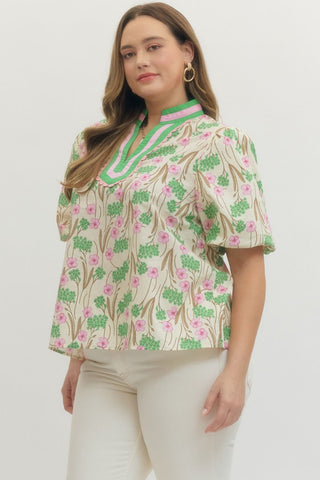 Woman wearing a floral blouse with green accents on a white background