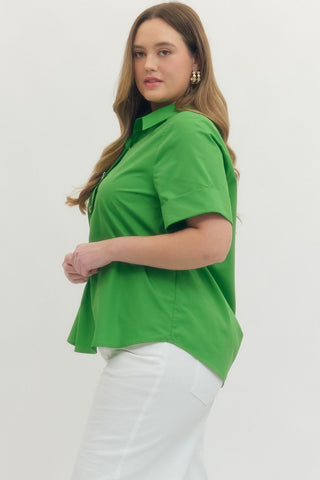 Woman wearing a green polo shirt and white pants on a plain background