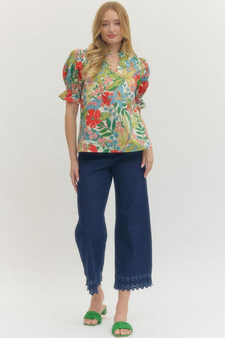 Woman wearing a colorful floral blouse and navy pants on a white background
