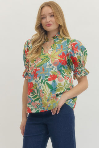 Woman wearing a colorful floral blouse with puff sleeves against a white background
