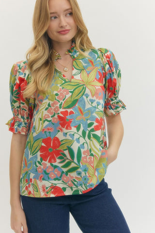 Woman wearing a colorful floral blouse with puff sleeves on a white background