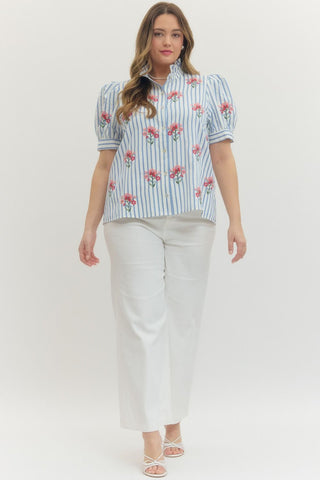 Woman wearing a floral blouse and white pants on a white background