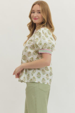 Woman wearing a floral blouse and green pants on a white background