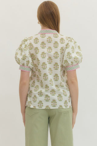 Person wearing a floral blouse and green pants on a plain background
