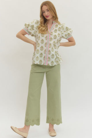 Woman wearing a floral top and green pants on a white background