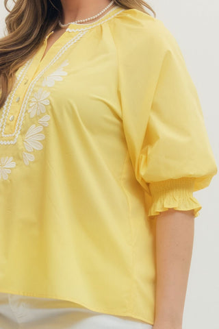 Yellow blouse with floral embroidery on a plain background