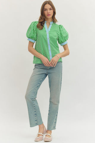 Woman wearing a green and white striped blouse with blue accents and light blue jeans on a white background