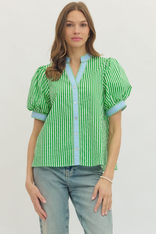 Woman wearing a green and white striped blouse with blue accents on a plain background