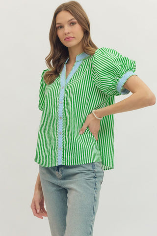 Woman wearing a green and white striped shirt with light blue accents on a plain background
