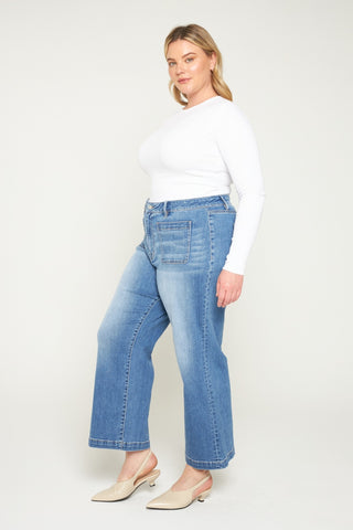 Woman wearing blue jeans and a white top on a white background