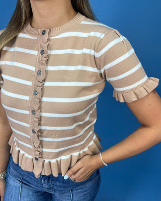 A woman wearing a beige and white horizontally striped short-sleeve knit top with ruffle trim along the front buttons, neck