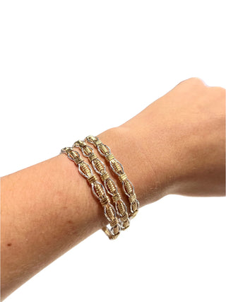 Gold bracelet on a wrist against a white background