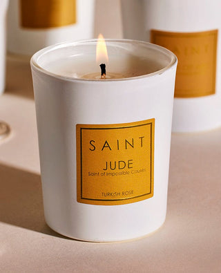 White candle with a gold label reading 'Saint Jude' on a light background