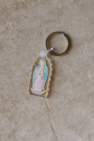 Keychain with a religious figure design on a beige surface