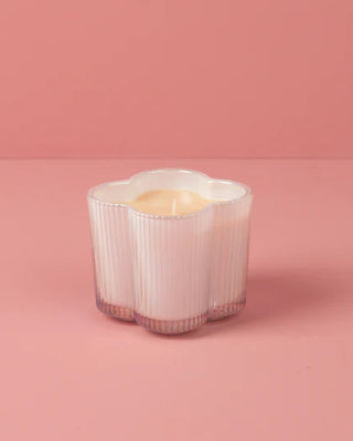 Candle in a decorative white holder on a pink background