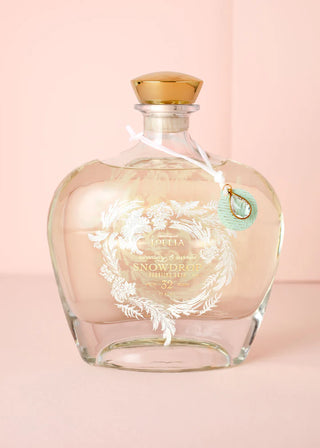 Glass bottle with gold cap and decorative label on a pink background