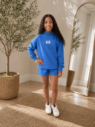 Youth Logo Lounge Top featuring a terrycloth interior, mock neckline, relaxed fit, and signature logo patch.