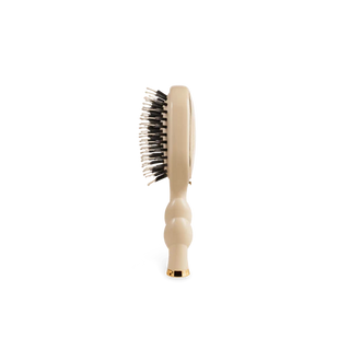 Beige hairbrush with black bristles on a white background