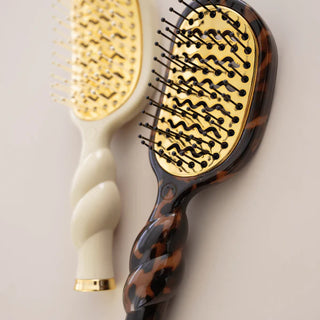 Two hairbrushes with tortoiseshell and beige handles on a light background