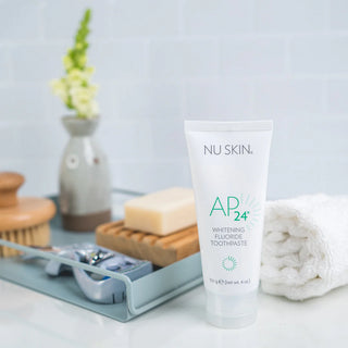 NU SKIN AP24 Whitening Fluoride Toothpaste on a bathroom counter with grooming items.