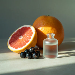 Fruit and a small bottle on a light surface with a neutral background