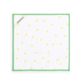 White napkin with yellow polka dots and green border on a white background
