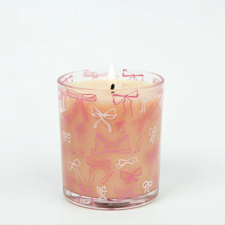 Candle in a glass jar with pink and white bow pattern on a white background